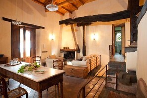 Un interior rústico con comedor, asientos y chimenea.