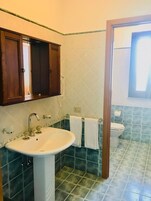 Un bagno con un lavandino su piedistallo, un water e un armadietto in legno.