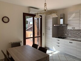 Una cucina moderna con zona pranzo, caratterizzata da un tavolo e sedie in legno, un piano cottura integrato e un'ampia finestra.
