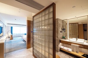 A modern hotel room with a large mirror, a bathroom with a vanity, and a view of the room's interior.