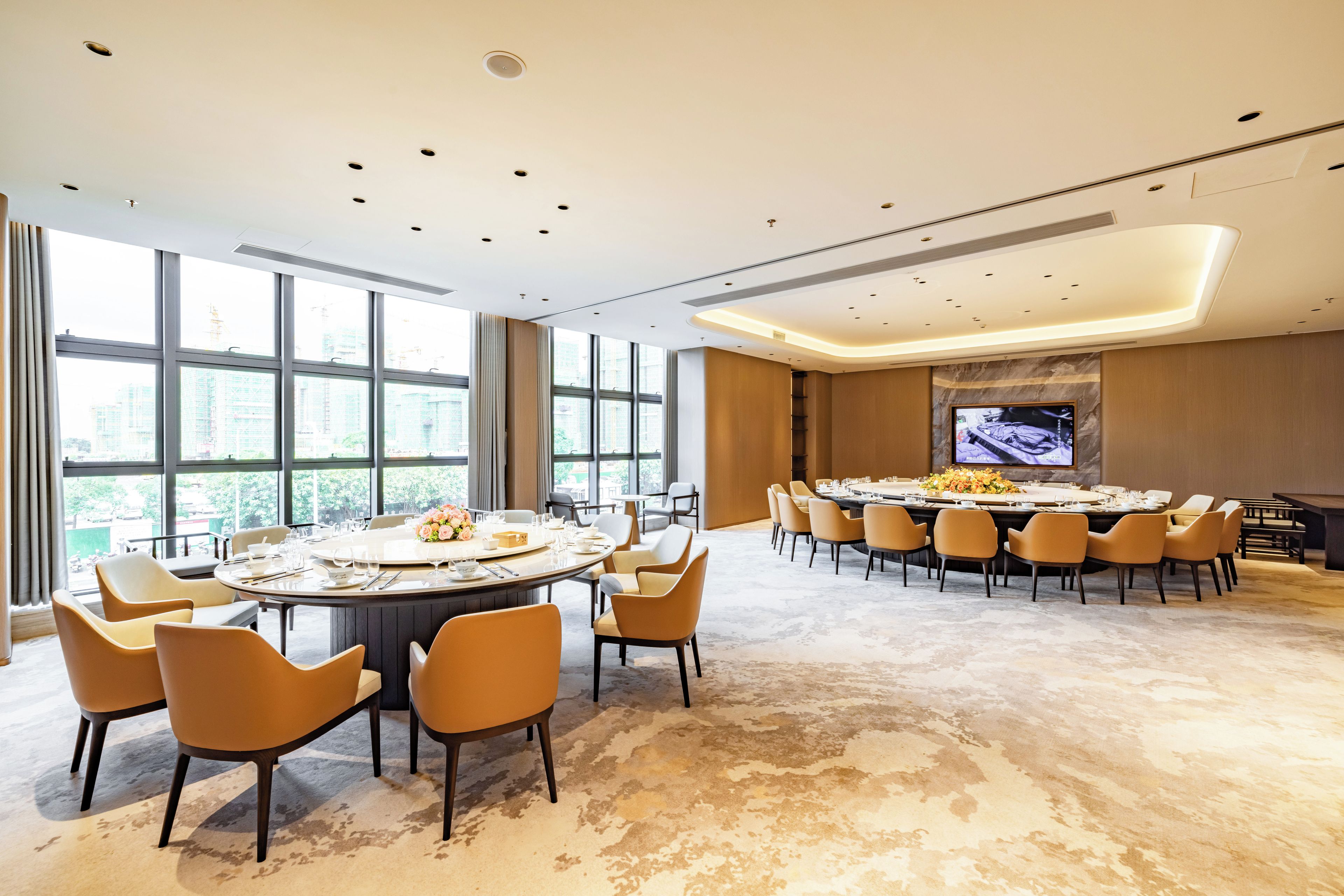 A conference room with a large oval table, multiple chairs, and a television screen.