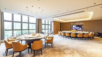 A conference room with a large oval table, multiple chairs, and a television screen.