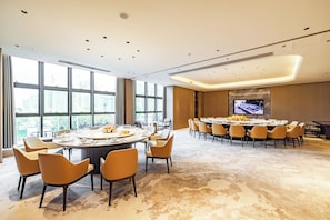 A conference room with a large oval table, multiple chairs, and a television screen. - Flower Season Hotel (Jiangmen)