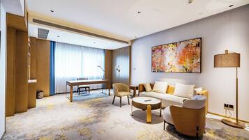 Una habitación de hotel moderna con un conjunto de sofás, una mesa de comedor y un cuadro abstracto grande.