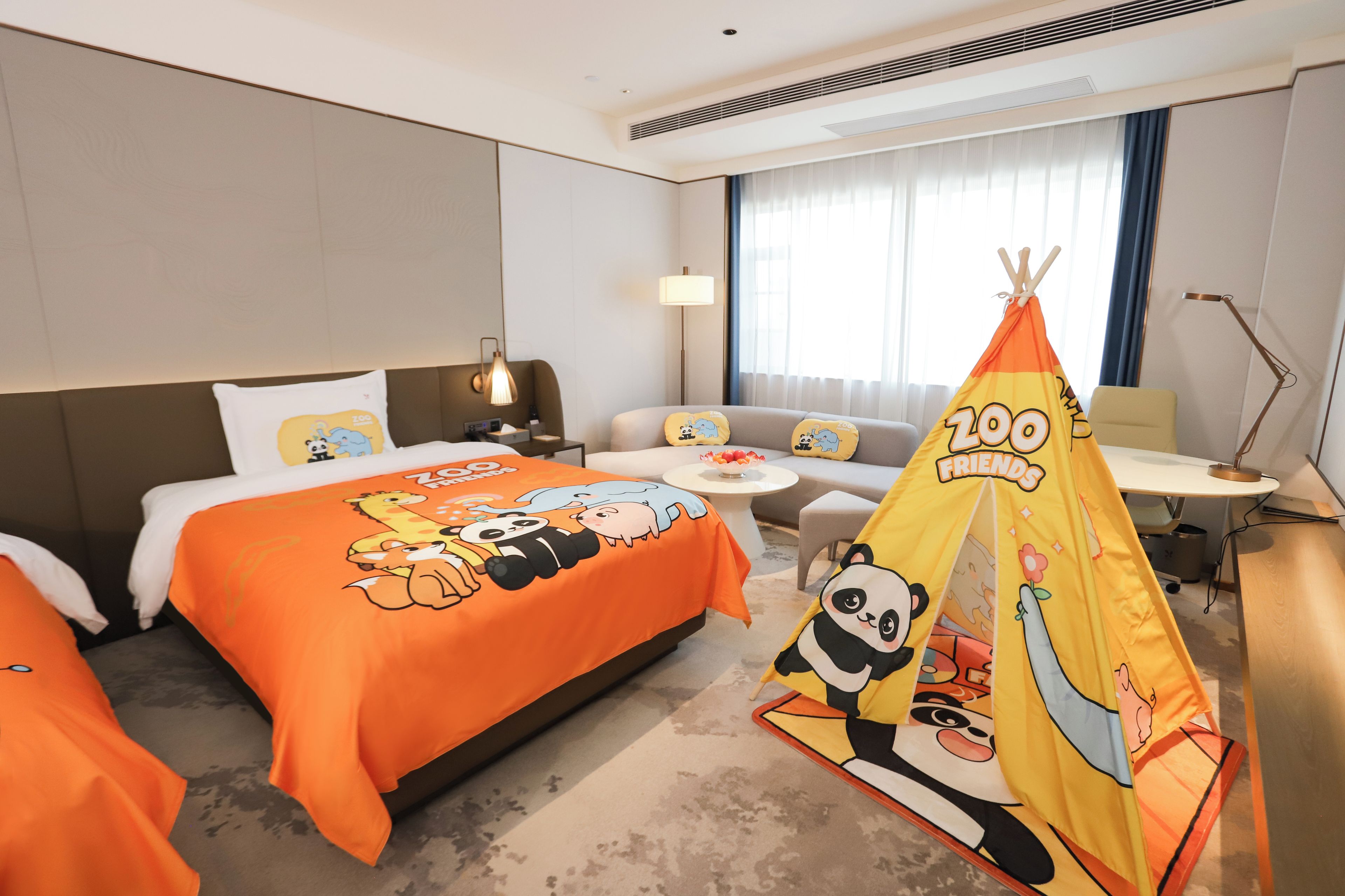 A hotel room with a bed, a sofa, a small table, a lamp, and a tent.