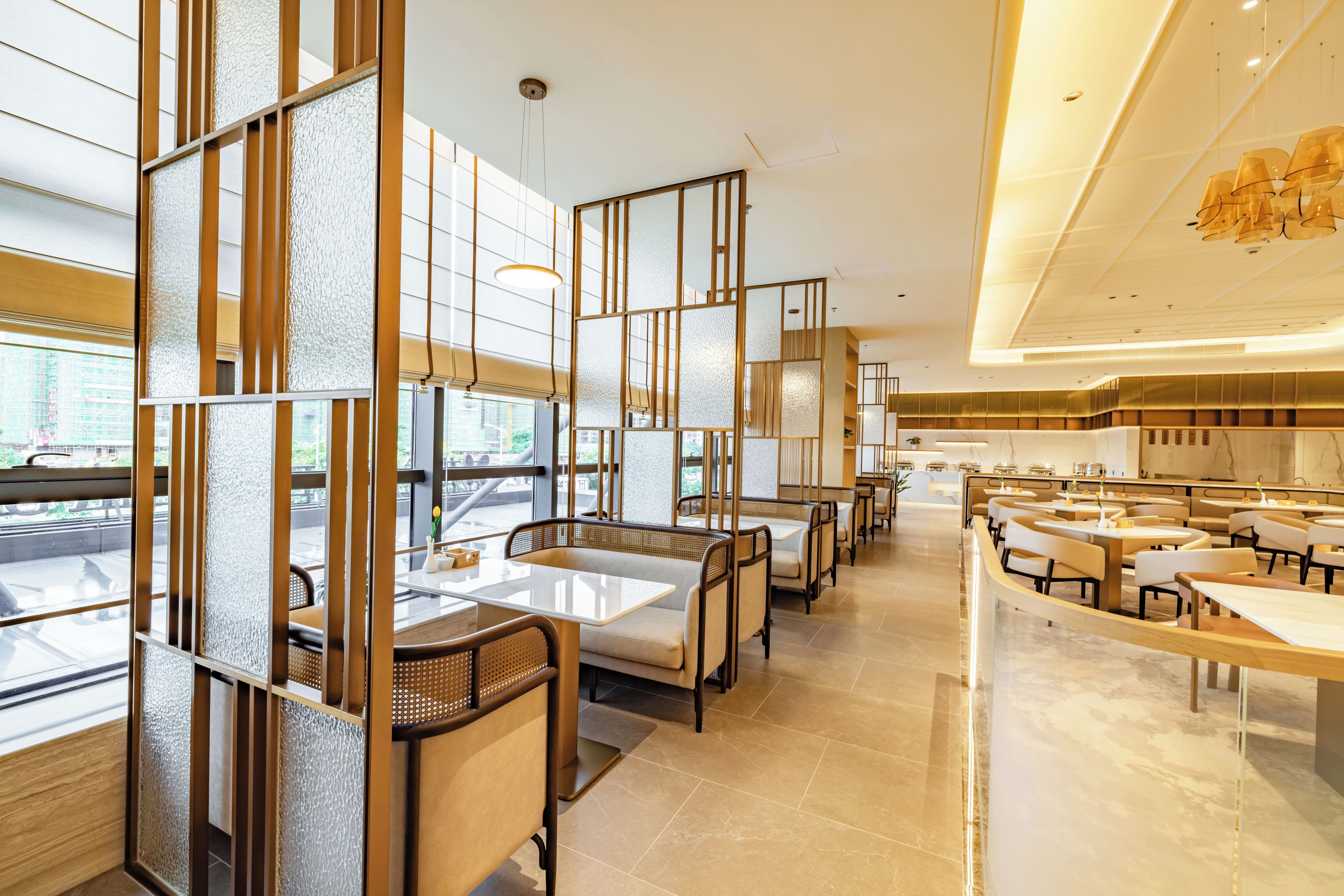 A modern restaurant interior with high tables and chairs, large windows, and a clean, minimalist design.