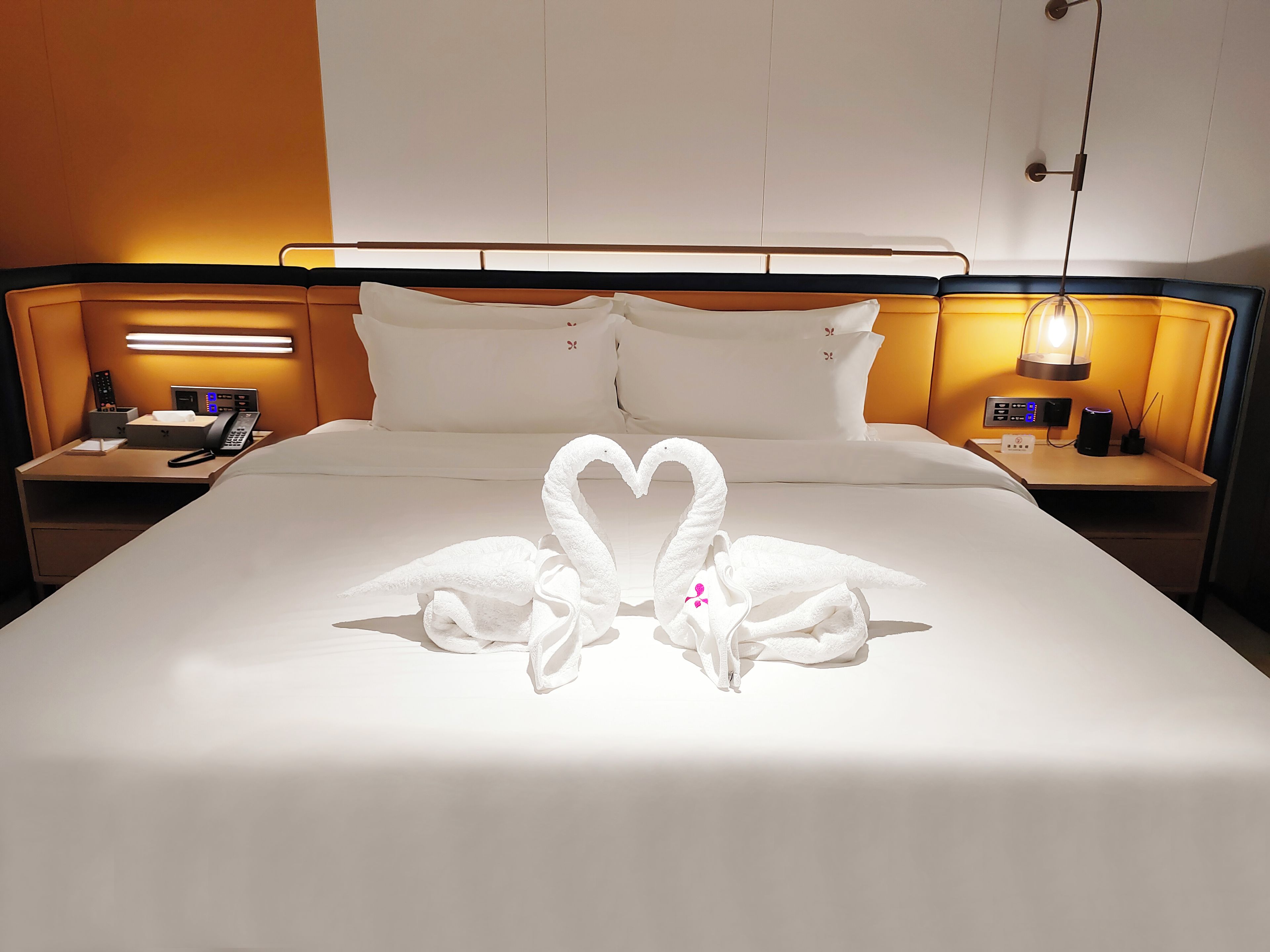 A hotel room with a bed, two nightstands, a telephone, and a wall-mounted lamp.