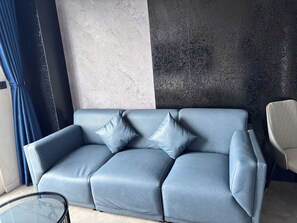 A modern living room with a grey sofa, two cushions, a glass coffee table, and a chair. - MINH PHUNG PHU QUOC (Phu Quoc)