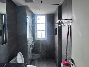 A modern bathroom with a shower, toilet, and a window providing natural light. - MINH PHUNG PHU QUOC (Phu Quoc)