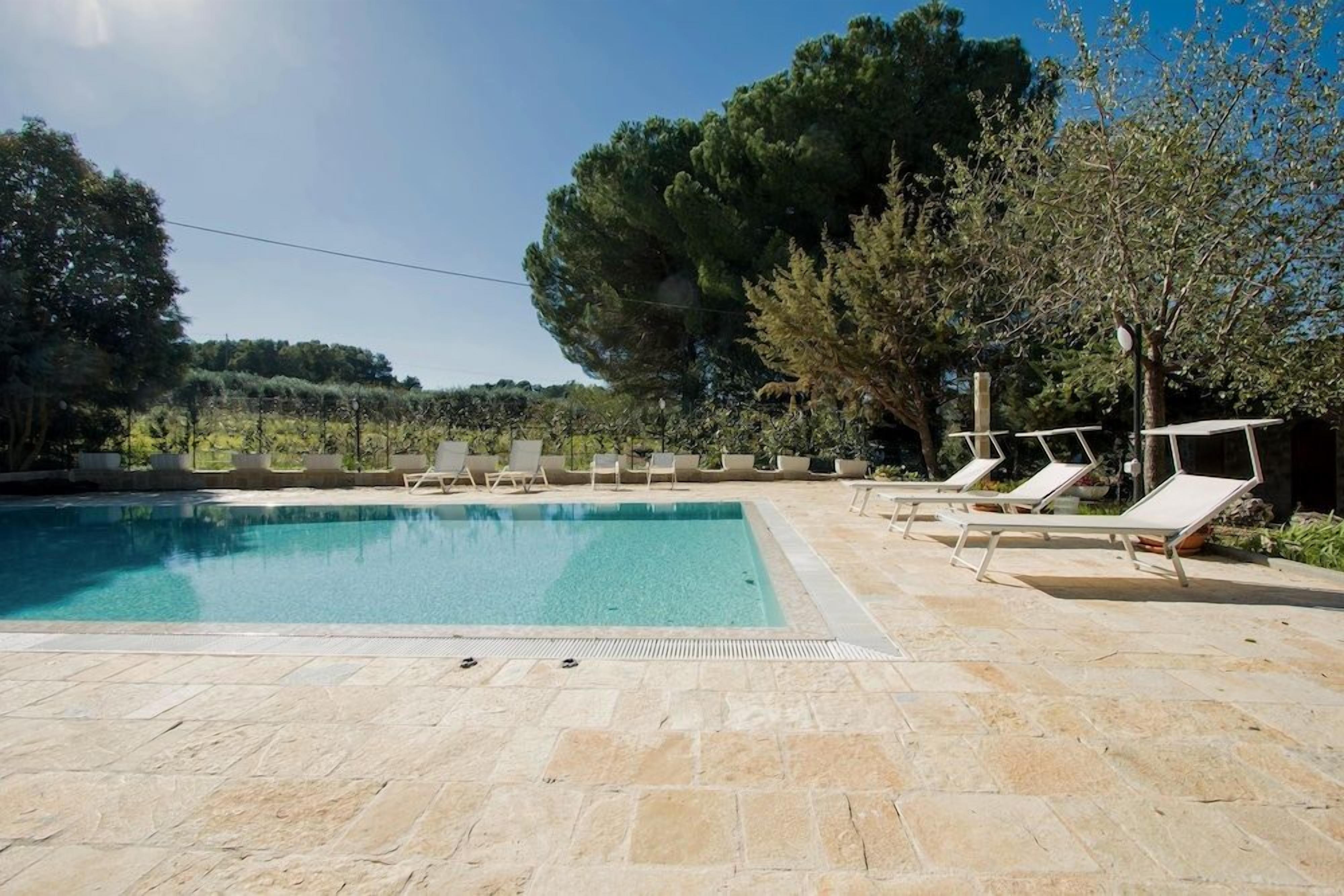 A swimming pool with lounge chairs and a stone deck.