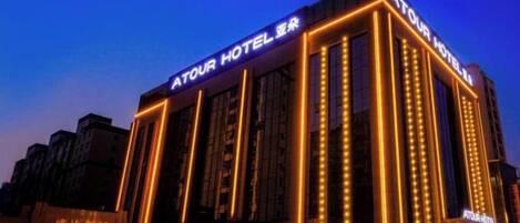 A hotel with a modern facade, illuminated signage, and a prominent entrance.