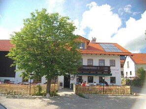 A building with a tiled roof, a balcony, and a tree in front.