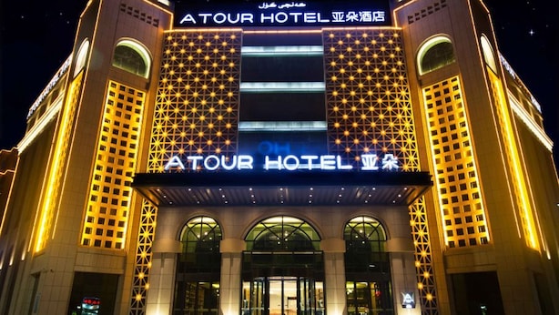 Un hotel con un cartello ben visibile che recita 'ATOUR HOTEL' e una grande facciata illuminata.