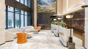 Spaziosa hall con arredamento moderno, caratterizzata da un'ampia finestra, una reception e zone relax.