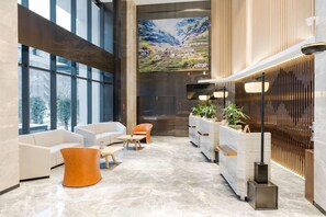 Eine großzügige Lobby mit modernem Design, ausgestattet mit einem großen Fenster, einer Rezeption und Sitzbereichen.