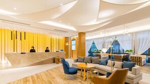 A modern hotel lobby with a reception desk, seating area, and large windows. - Atour Hotel (Xuzhou)