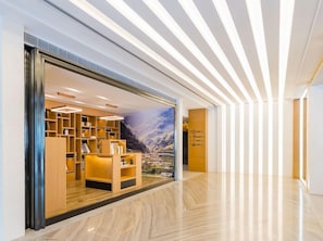 A modern hotel lobby with a wooden reception desk, a large mural of a mountainous landscape, and a sleek, light-colored floor. - Atour Hotel (Xuzhou)