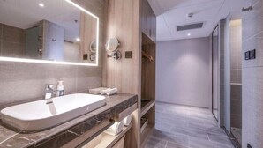 A modern bathroom with a large sink, mirror, and shower area. - Atour Hotel (Xuzhou)