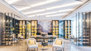 A modern library with bookshelves, a large painting, and a central table with two chairs. - Atour Hotel (Nantong)