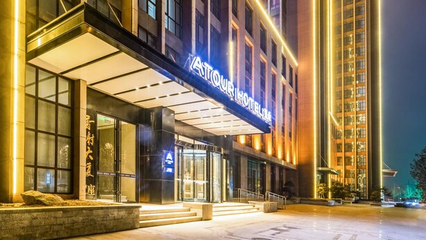 Un hotel modern amb una entrada destacada, grans finestres de vidre i una façana ben il·luminada.