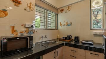 A modern kitchen with a microwave, toaster, and kettle on the counter, a window with a view of greenery, and decorative wall art.