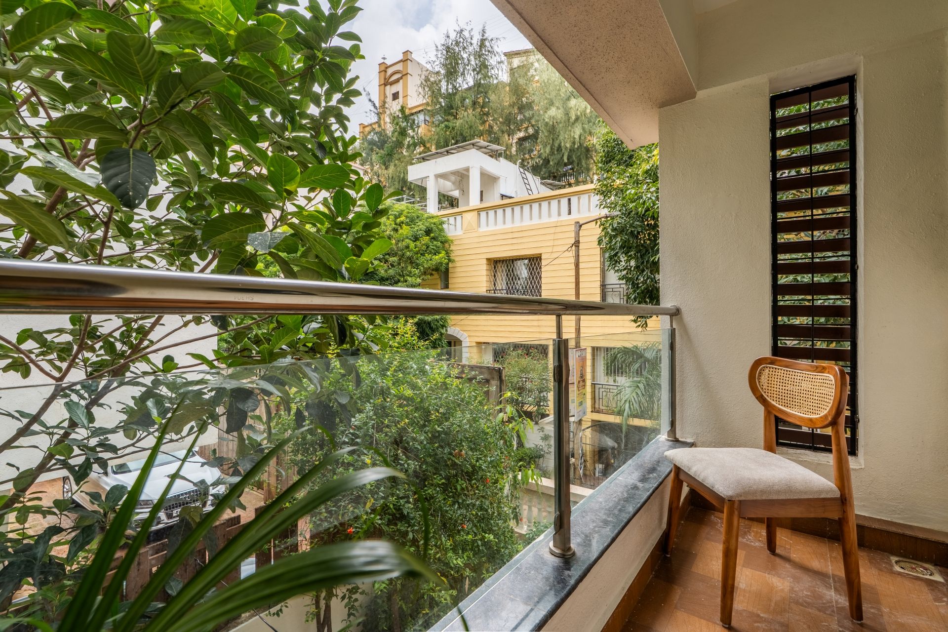 A balcony with a view of a building, a chair, and a railing.