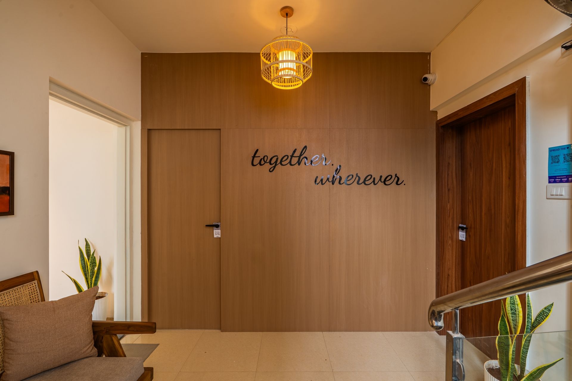 A wooden door with a motivational quote, a hanging light fixture, and a staircase with a handrail.