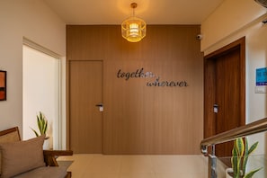 A wooden door with a motivational quote, a hanging light fixture, and a staircase with a handrail. - LiveAway Pune (Viman Nagar) by PACK (Pune)