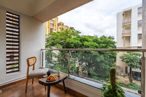 A balcony with a chair, a small table, and a cactus plant.