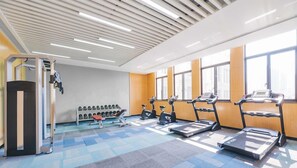 Ein Fitnessraum mit Laufbändern, Crosstrainern und einem Gewichtsständer.