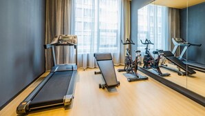 Een moderne sportschool met loopbanden, hometrainers en een roeiapparaat.