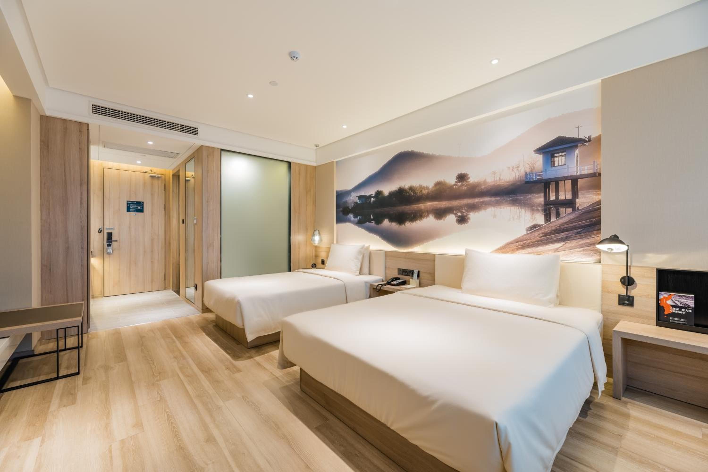 Une chambre d’hôtel avec deux lits, une grande fresque murale, un bureau et une table de chevet.