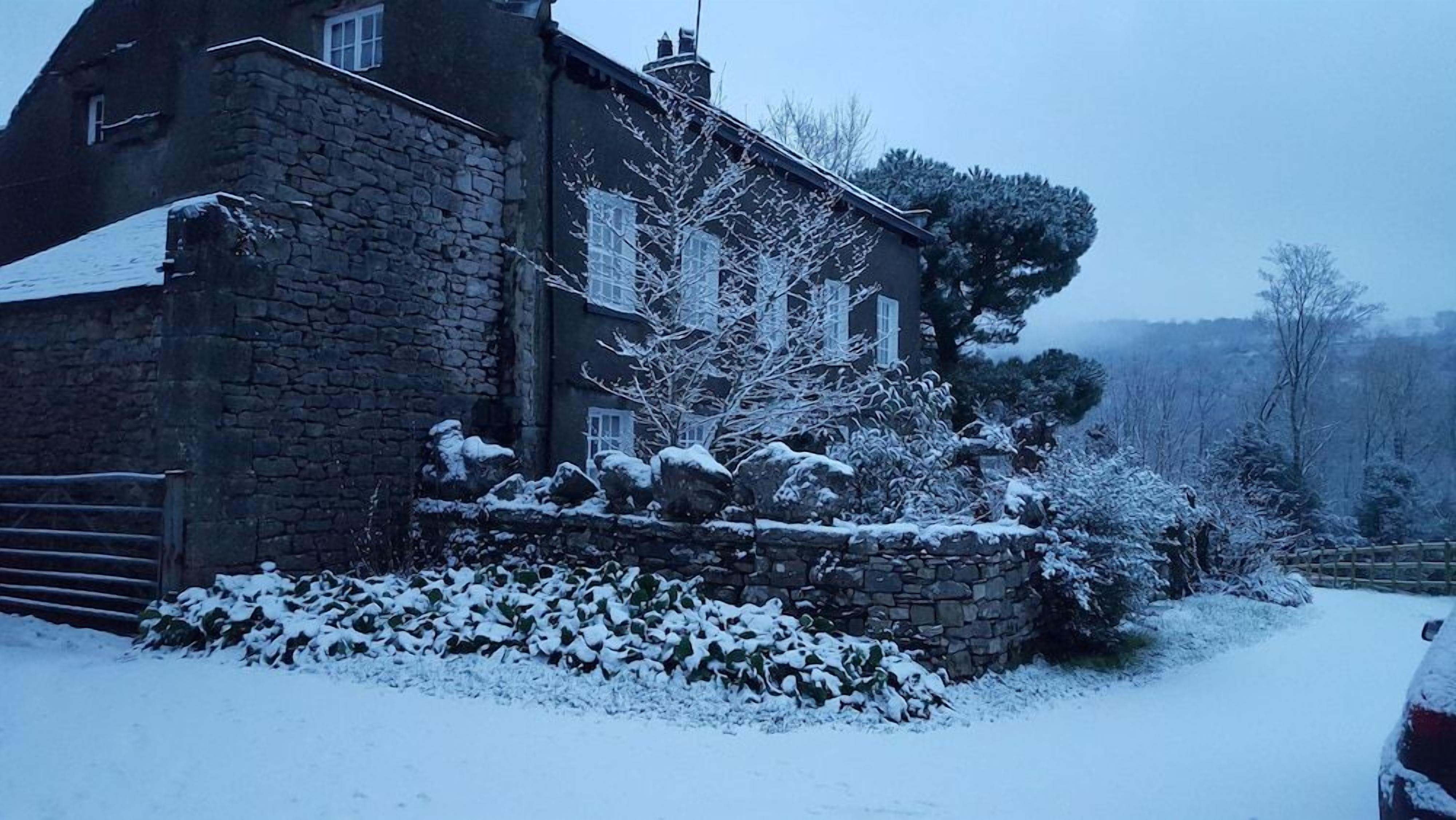 A stone house with snow-covered exterior and a driveway.