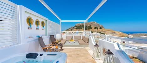 Une terrasse sur le toit avec un jacuzzi, un espace salon et une vue sur une colline.