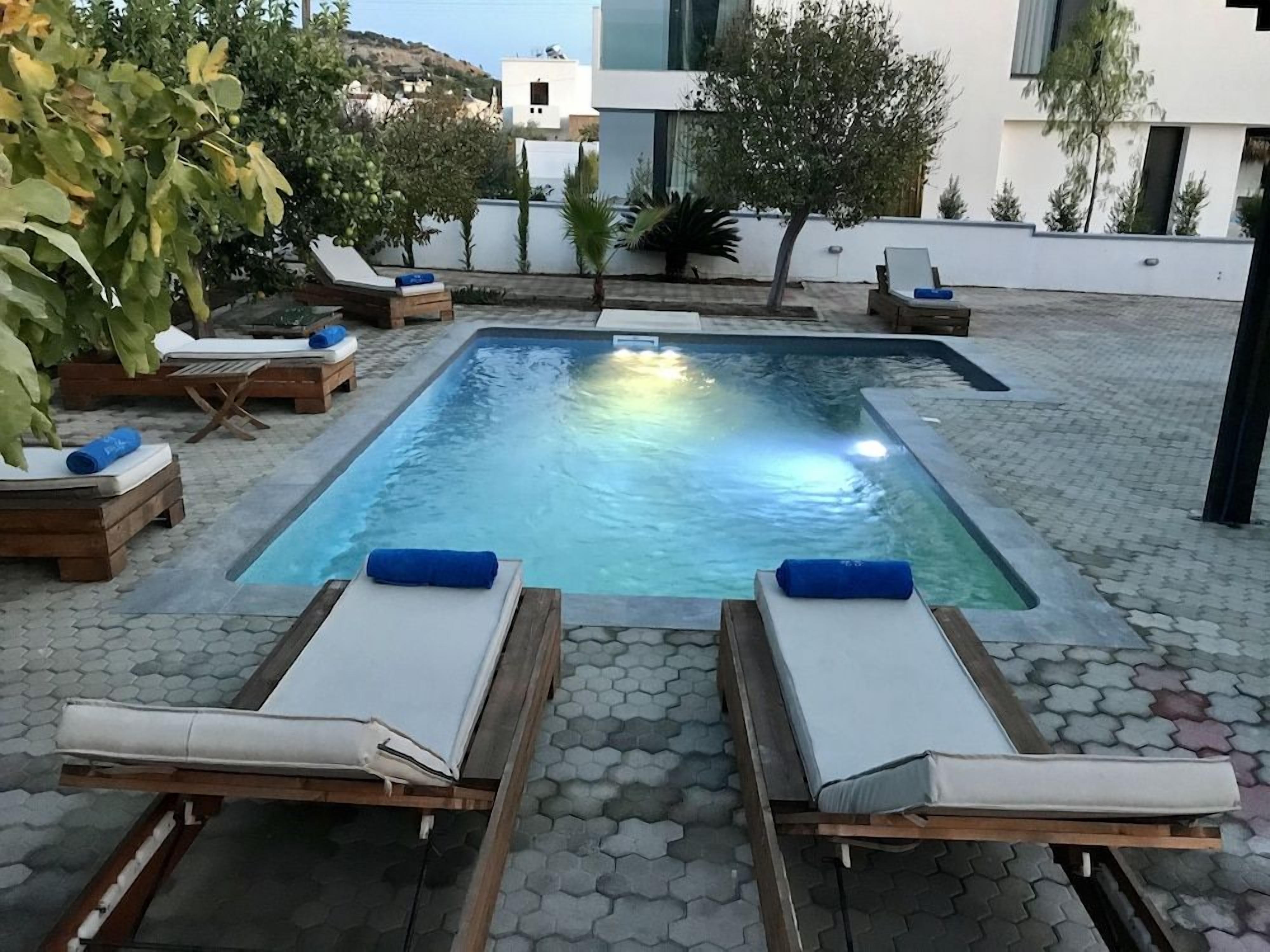 Une piscine rectangulaire avec des chaises longues et une terrasse carrelée.