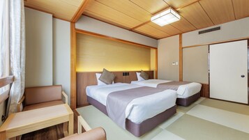 A hotel room with two beds, a seating area, and a traditional Japanese-style sliding door.