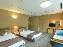A hotel room with two beds, a desk with a television, a chair, and a mirror.
