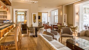 A spacious lounge area with a bar, seating arrangements, and a view of the outside.
