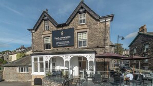 A stone building with a sign for 'The Lamplighter Dining Rooms' offering a restaurant, lounge, bar, terrace, and rooms.