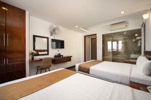 Une chambre d’hôtel avec deux lits, un bureau, une chaise, une télévision et une salle de bain avec une douche en verre.