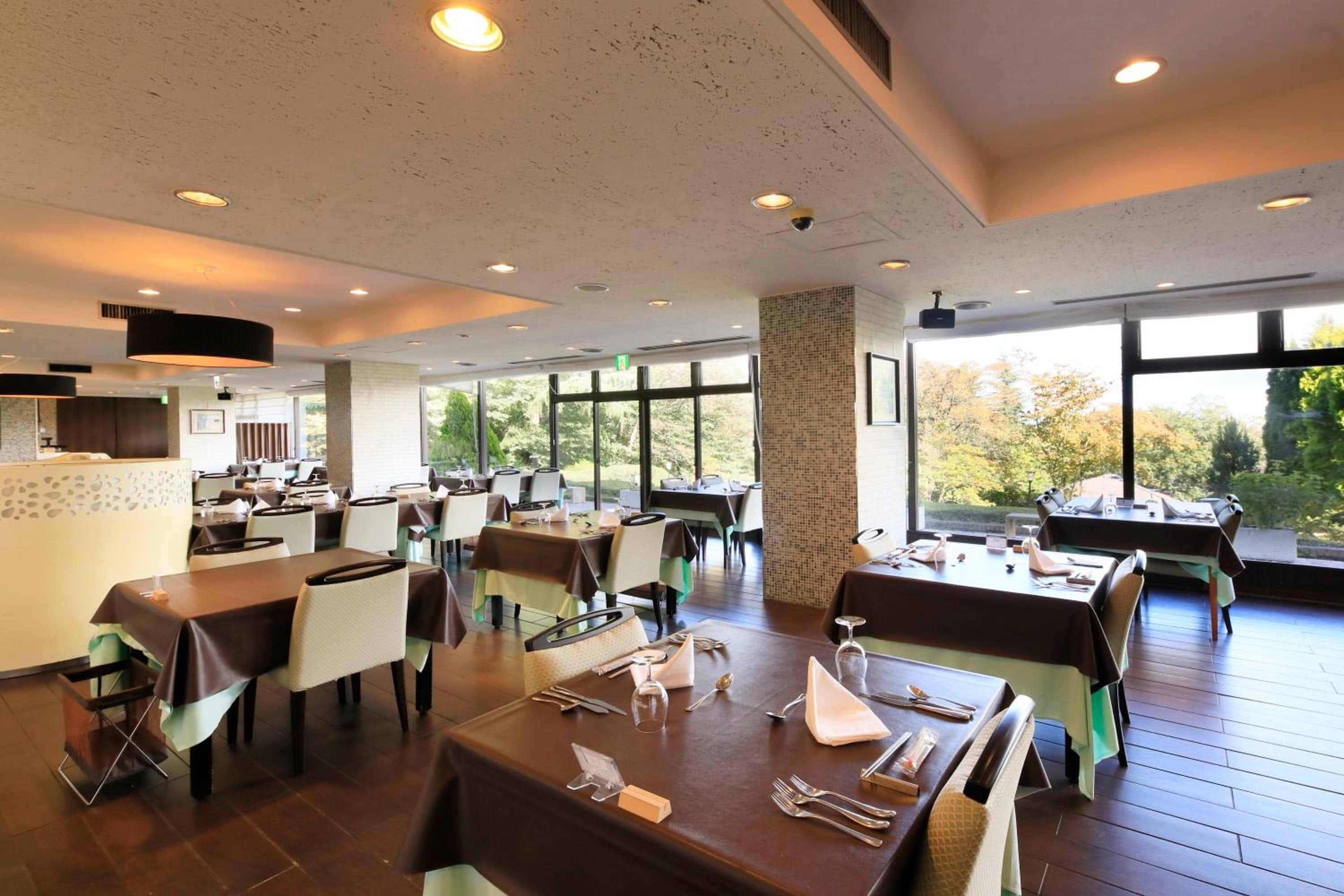 Un restaurante con varias mesas, sillas y una zona de cocina.