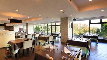 Un restaurante con varias mesas, sillas y una zona de cocina.
