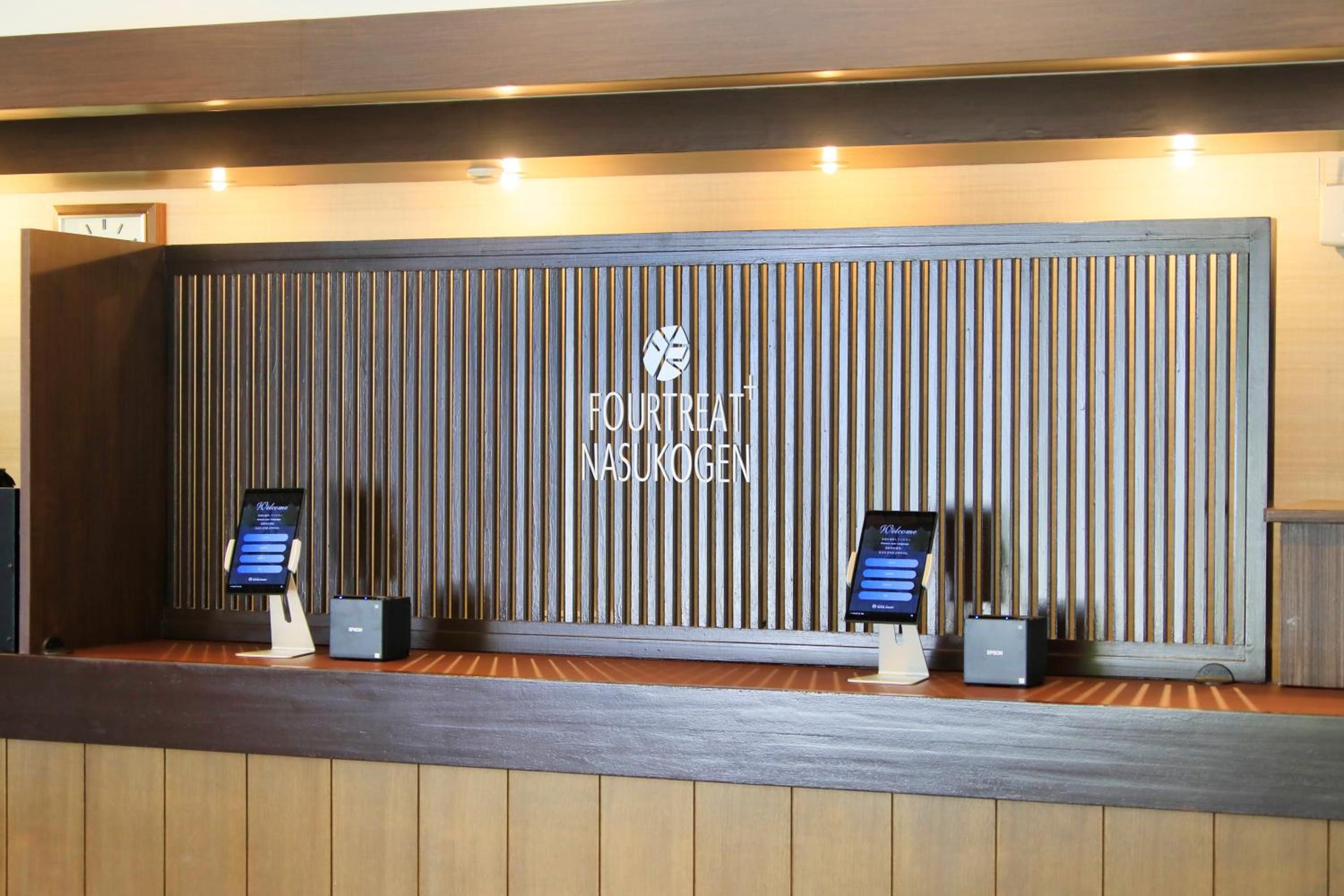 Una recepción con un panel de madera vertical y el texto 'FOURTREAT NASUKOGEN' en la pared.
