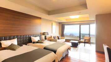 Habitación de hotel con dos camas, un sofá, un balcón y un ventanal grande.
