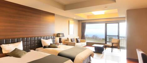 Habitación de hotel con dos camas, un sofá, un balcón y un ventanal grande.