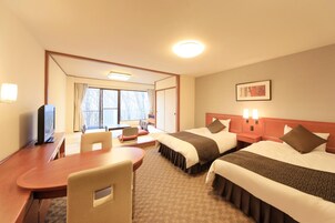 Habitación de hotel con dos camas, un escritorio, una silla y un televisor.