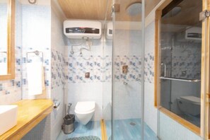Un bany amb dutxa de vidre, vàter i un lavabo.