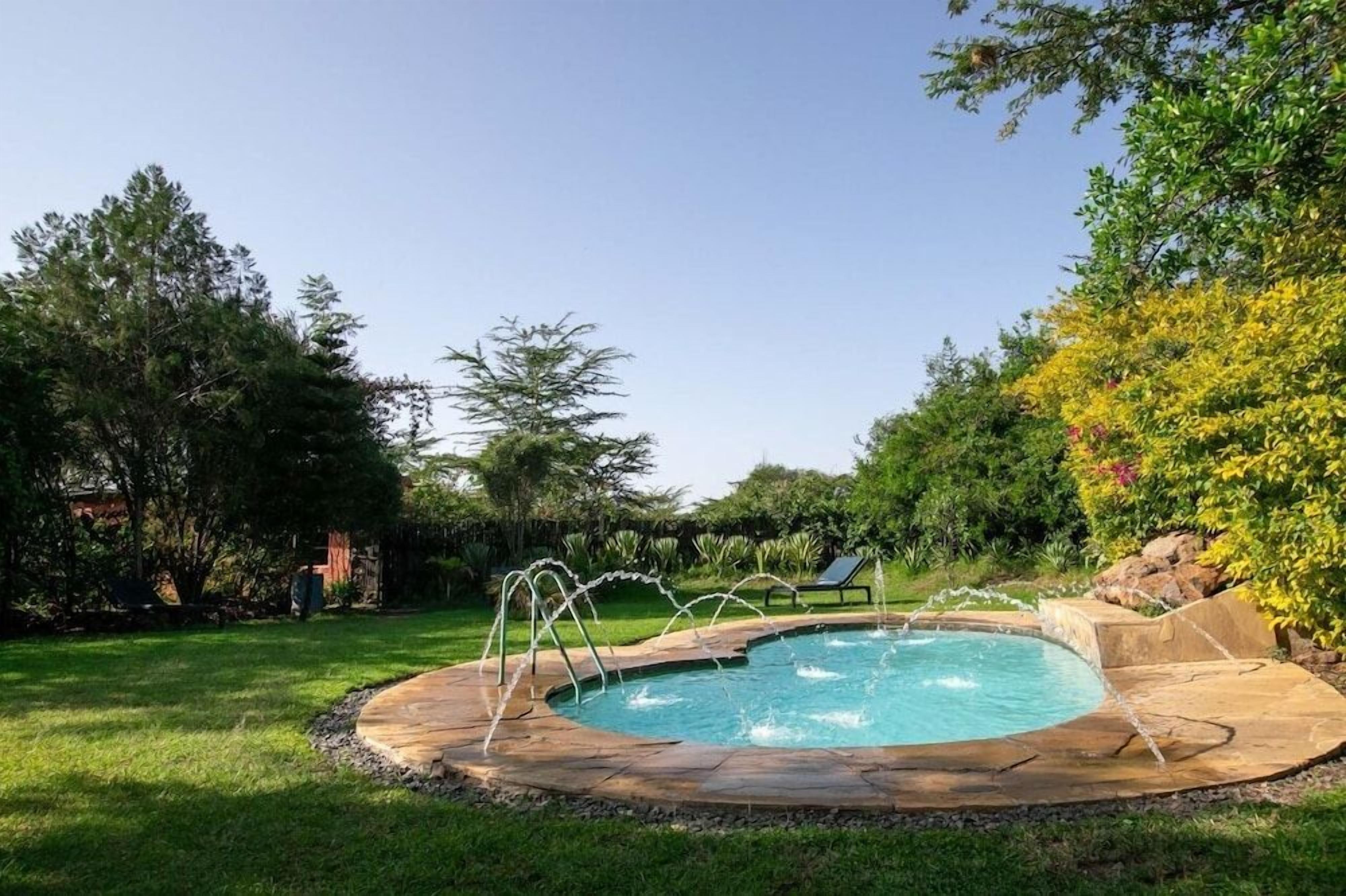 A swimming pool with a stone edge, surrounded by grass and trees.