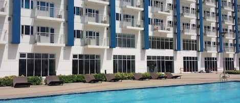 A hotel with a swimming pool, multiple balconies, and a modern architectural design.