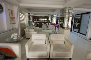 A modern living room with a sofa set, a glass coffee table, and a bar area in the background.